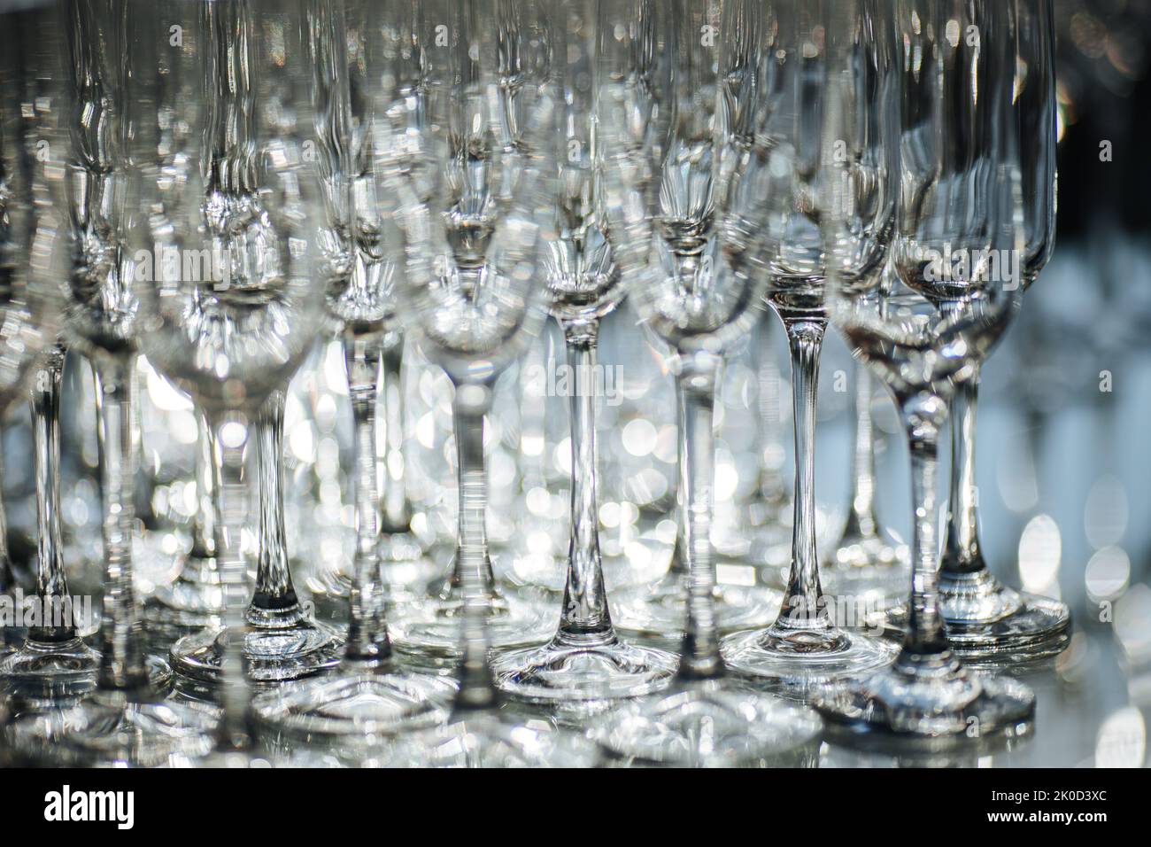 Gruppe leerer und transparenter Sektgläser in einem Restaurant. Reinigen Sie die Gläser auf einem Tisch, der vom Barkeeper für Champagner zubereitet wurde. Catering für die Veranstaltungsvorbereitung, leere Gläser für Getränke. Stockfoto