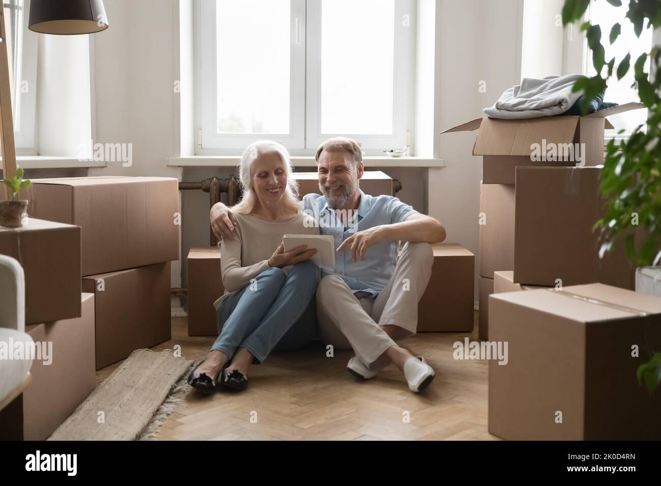 Glückliches altes Paar neuer Hausbesitzer, die auf dem Heizboden sitzen Stockfoto