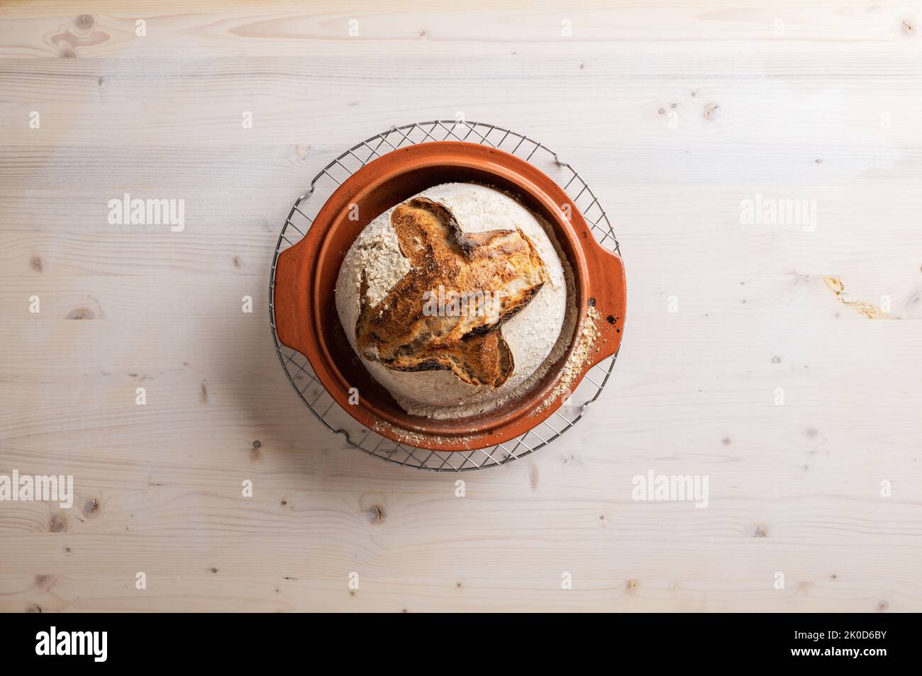 Draufsicht auf köstliche Bio hausgemachtes Sauerteig Brot frisch gebacken in Tontopf auf Holz Hintergrund platziert. Stockfoto