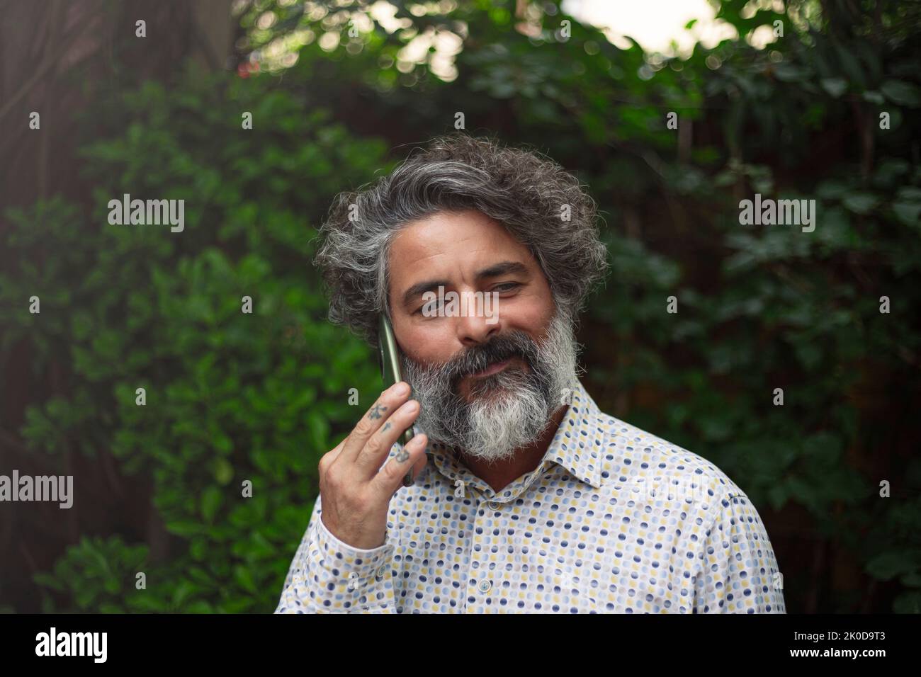 Hipster-Geschäftsmann im Gespräch mit einem zufriedenen Gesicht auf seinem Handy Stockfoto