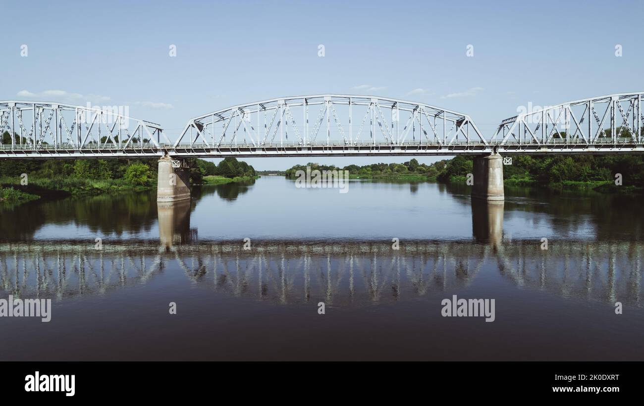 Symmetrische Ansicht der Stahltrassebrücke für Züge über den Fluss Stockfoto
