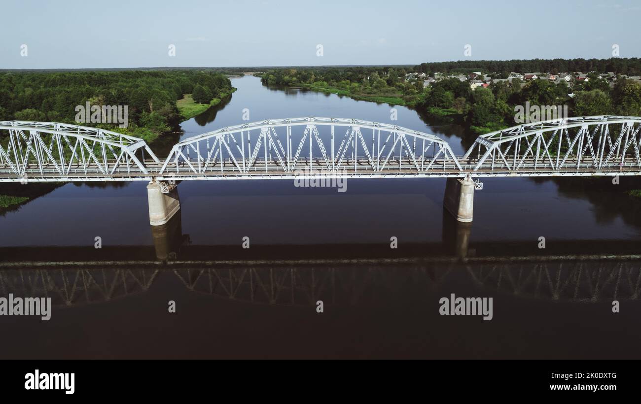 Symmetrische Luftaufnahme der Stahltraversenbrücke für Züge über den Fluss Stockfoto