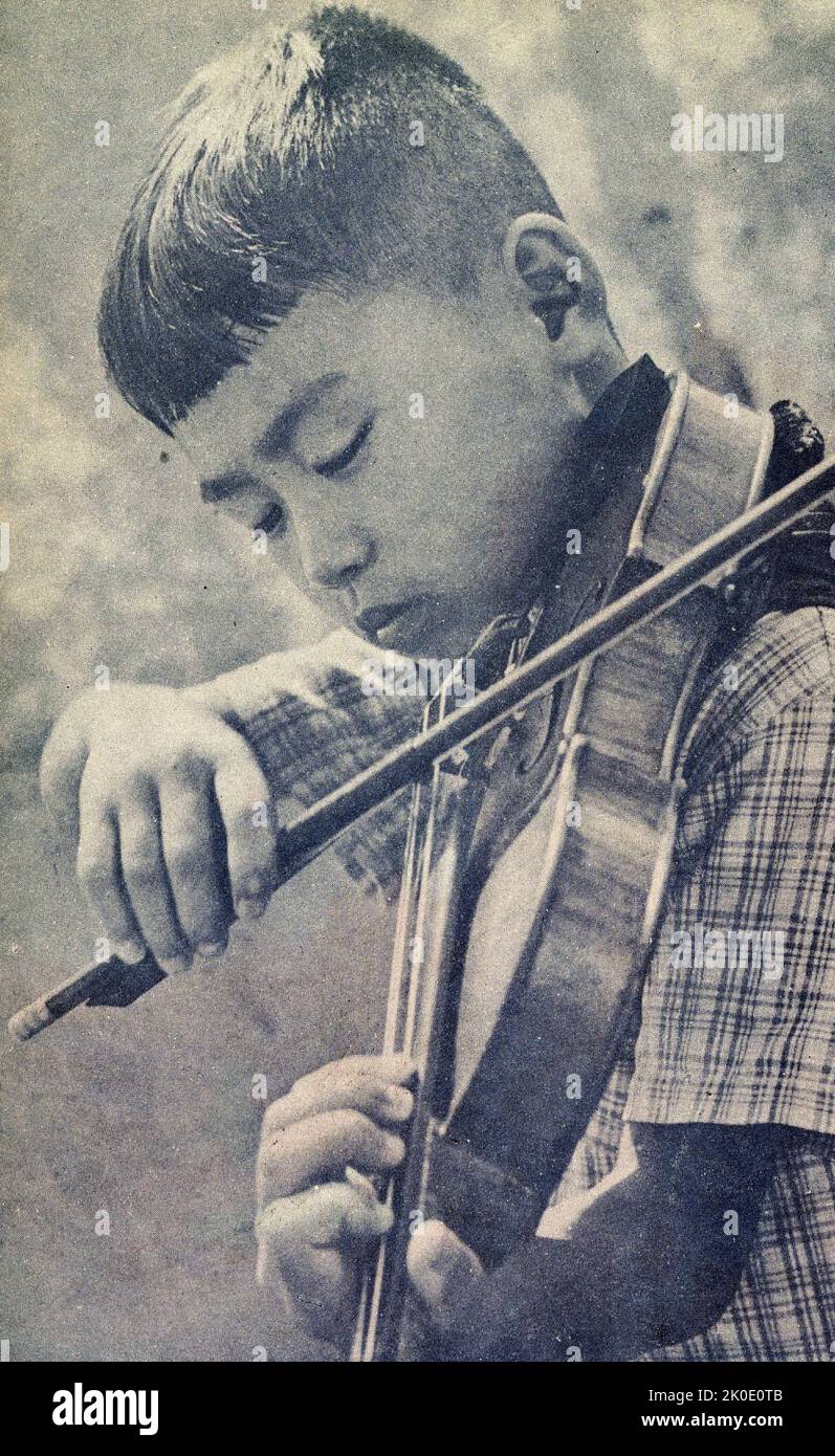 Propagandafoto mit einem nordkoreanischen Jungen, der eine Geige spielt, 1962. Stockfoto