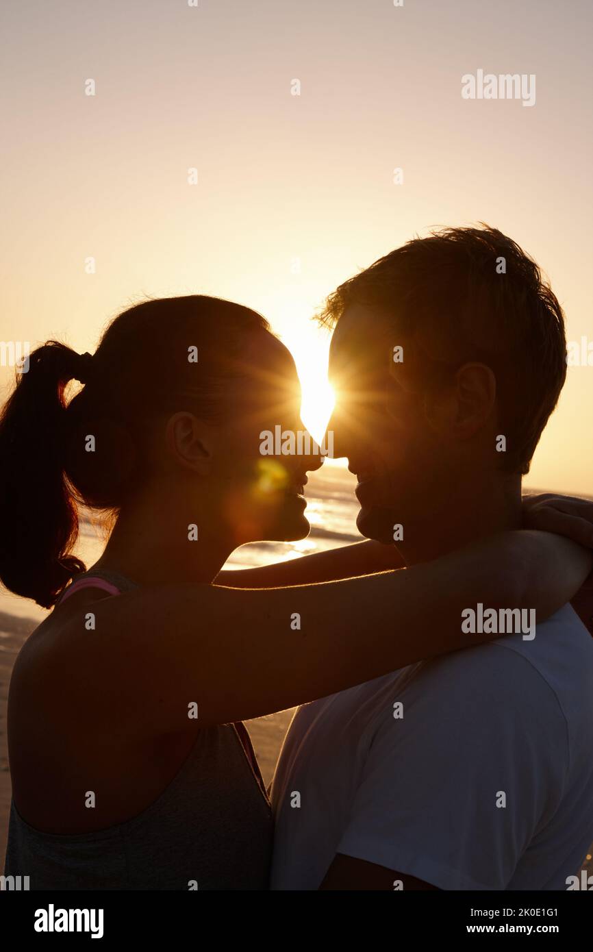 Ich wünschte mir, dieser Moment könnte ewig dauern. Silhouette eines Paares, das bei Sonnenuntergang am Strand romantisch ist. Stockfoto