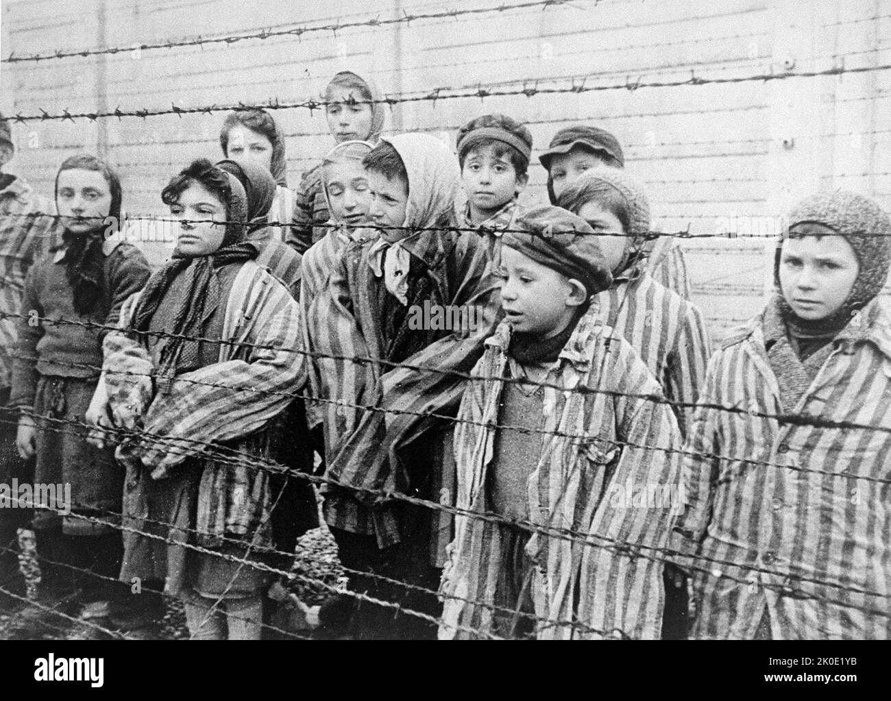 Standbild aus dem sowjetischen Film über die Befreiung von Auschwitz, aufgenommen von der Filmeinheit der Ersten Ukrainischen Front, aufgenommen 1945 von Alexander Voronzow und anderen aus seiner Gruppe. Überlebende von Auschwitz, die in Häftlingsjacken in Erwachsenengröße leben, stehen hinter einem Stacheldrahtzaun. Stockfoto