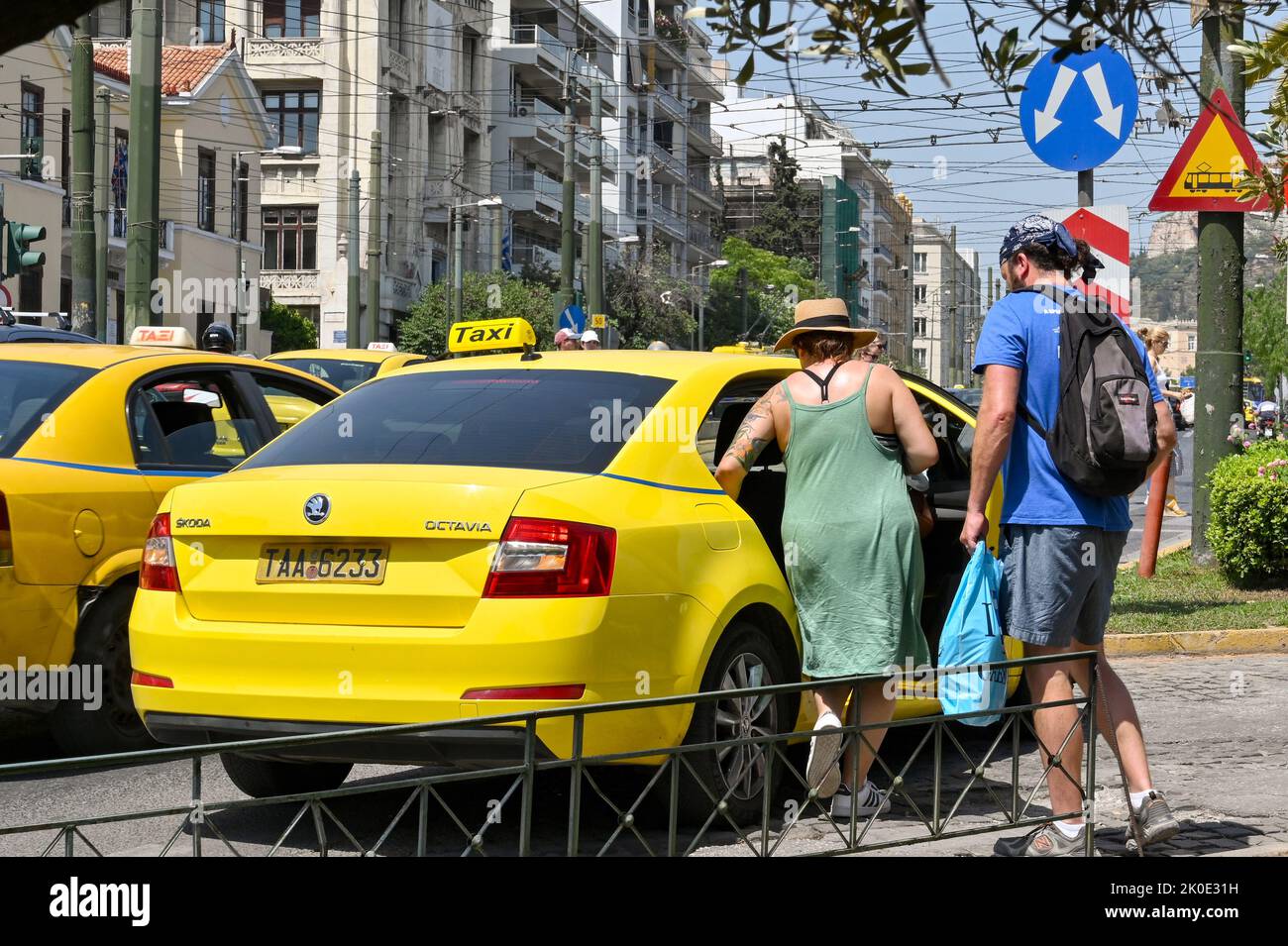 Athen, Griechenland - 2022. Mai: Zwei Personen steigen in ein gelbes Taxi auf einer der Straßen der Stadt Stockfoto
