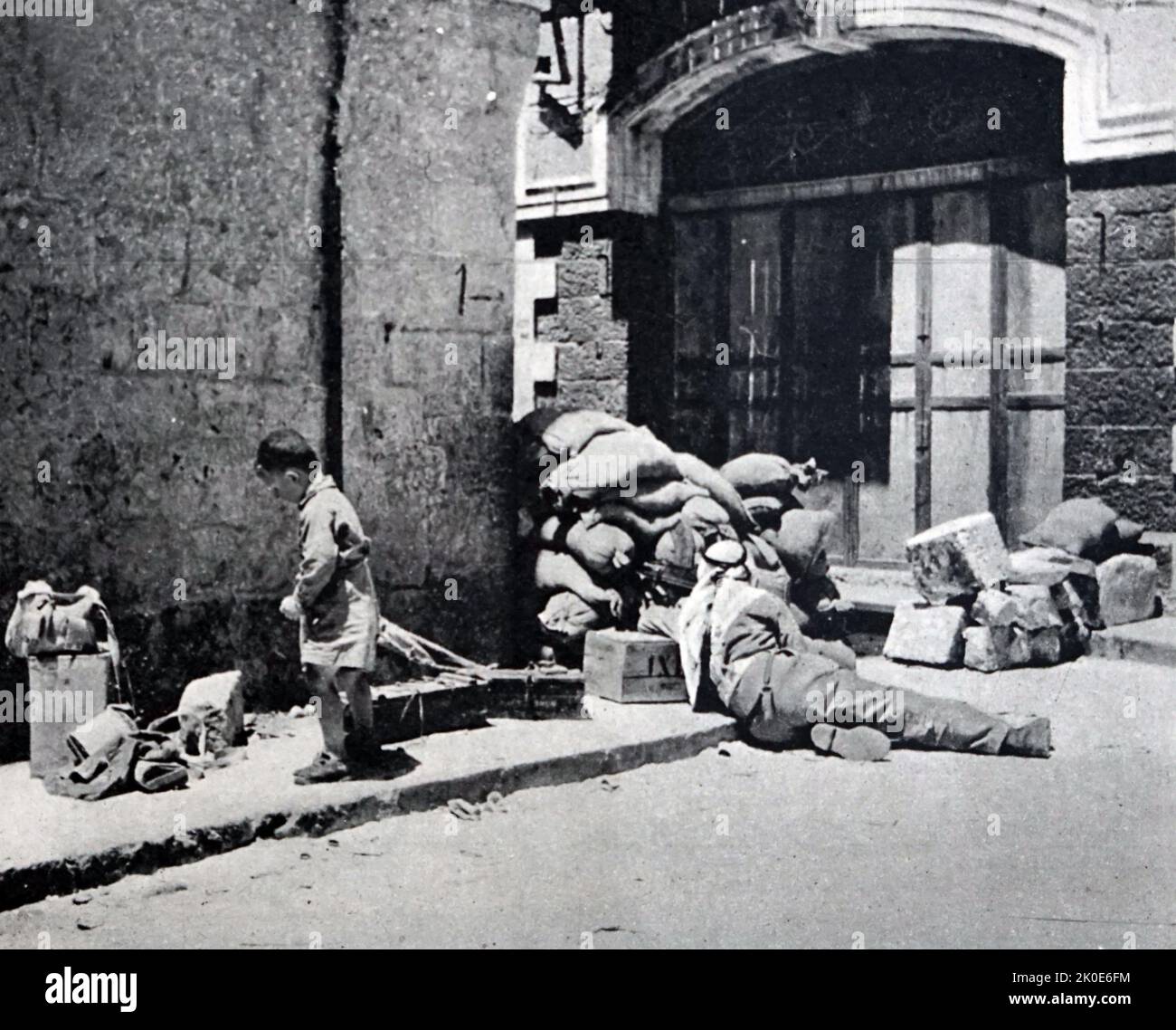Israel Unabhängigkeitskrieg: 1948. Mai arabischer Kämpfer auf den Straßen Jerusalems, als ein Junge in den Trümmern sucht. Stockfoto