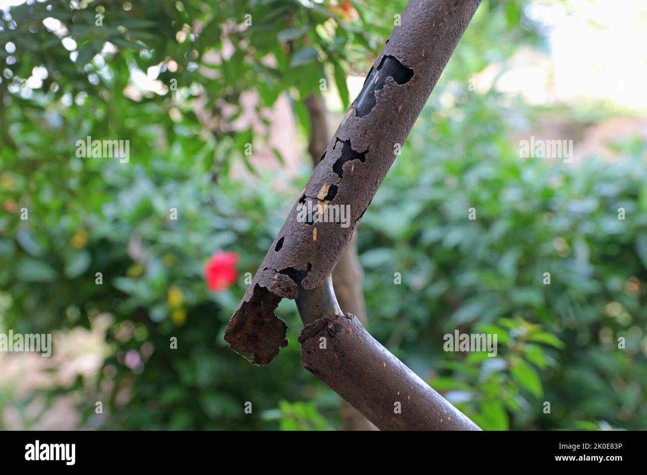 Eine verrostete Metallleitung mit einem Elektrokabel. Stockfoto
