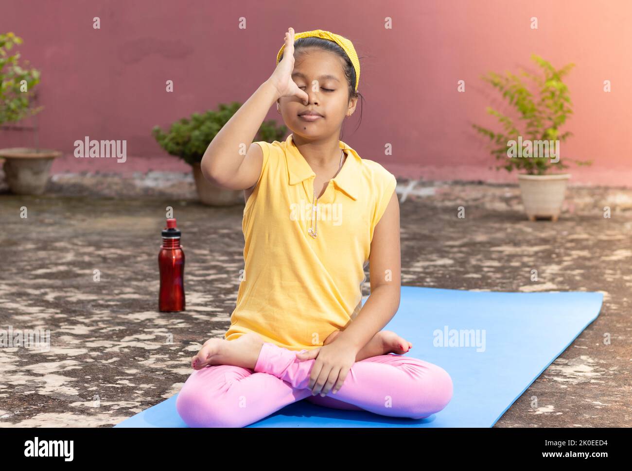 Ein indisches Mädchen, das im Freien Pranayama anulom vilom auf einer Yogamatte praktiziert Stockfoto