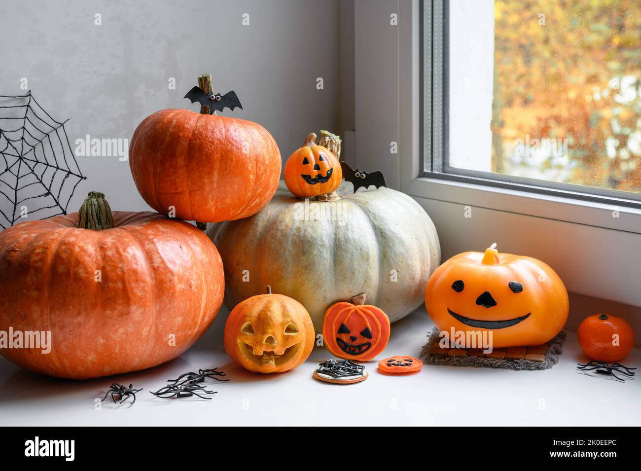 Halloween Stillleben am Fenster zu Hause. Gemüseset, orangefarbene Kürbisse, Süßigkeiten und Dekorationen auf weißem Fensterbrett auf Hallowen. Konzept von Oktober, f Stockfoto