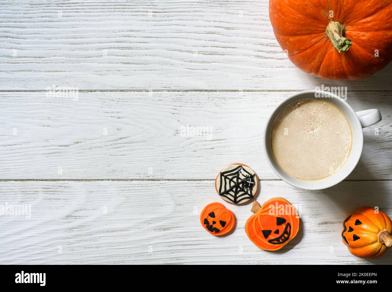 Halloween Hintergrund, Tasse Kaffee und Süßigkeiten auf Holztisch, Draufsicht. Orangefarbener Kürbis und Kekse auf weißen Holzplanken mit Platz. Party, Saison, O Stockfoto