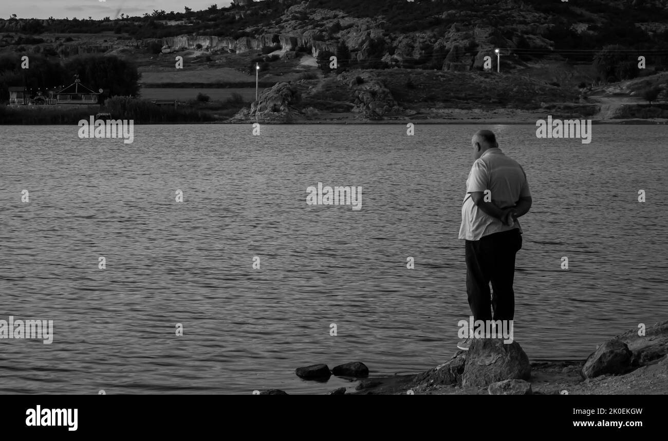 Trauriger Mann, der allein am See steht. Foto des Konzepts „Depression“. Selektiver Fokus. Stockfoto