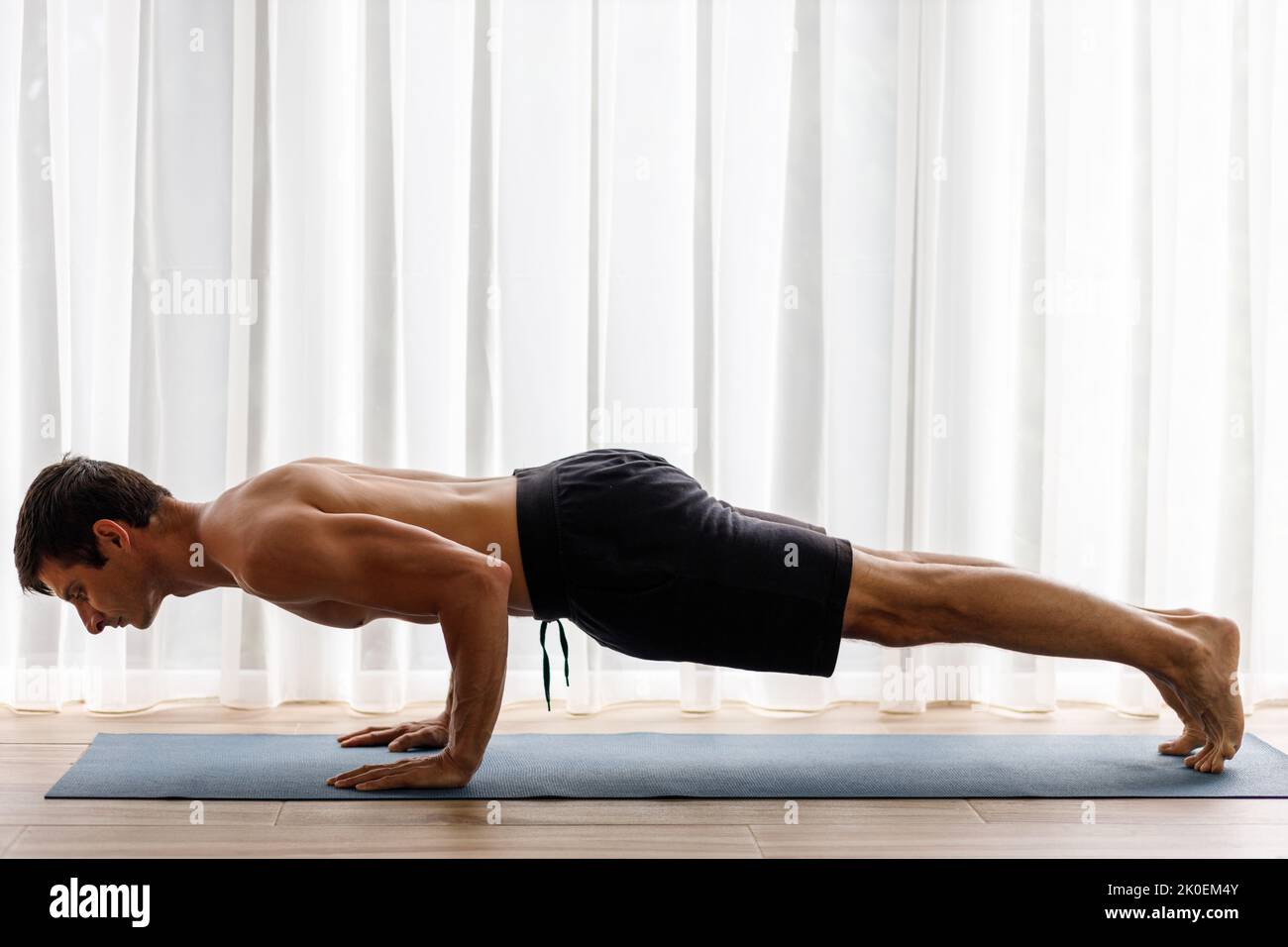 Mann mittleren Alters, der während seiner morgendlichen körperlichen Routine Chaturanga-Yoga-Pose macht Stockfoto