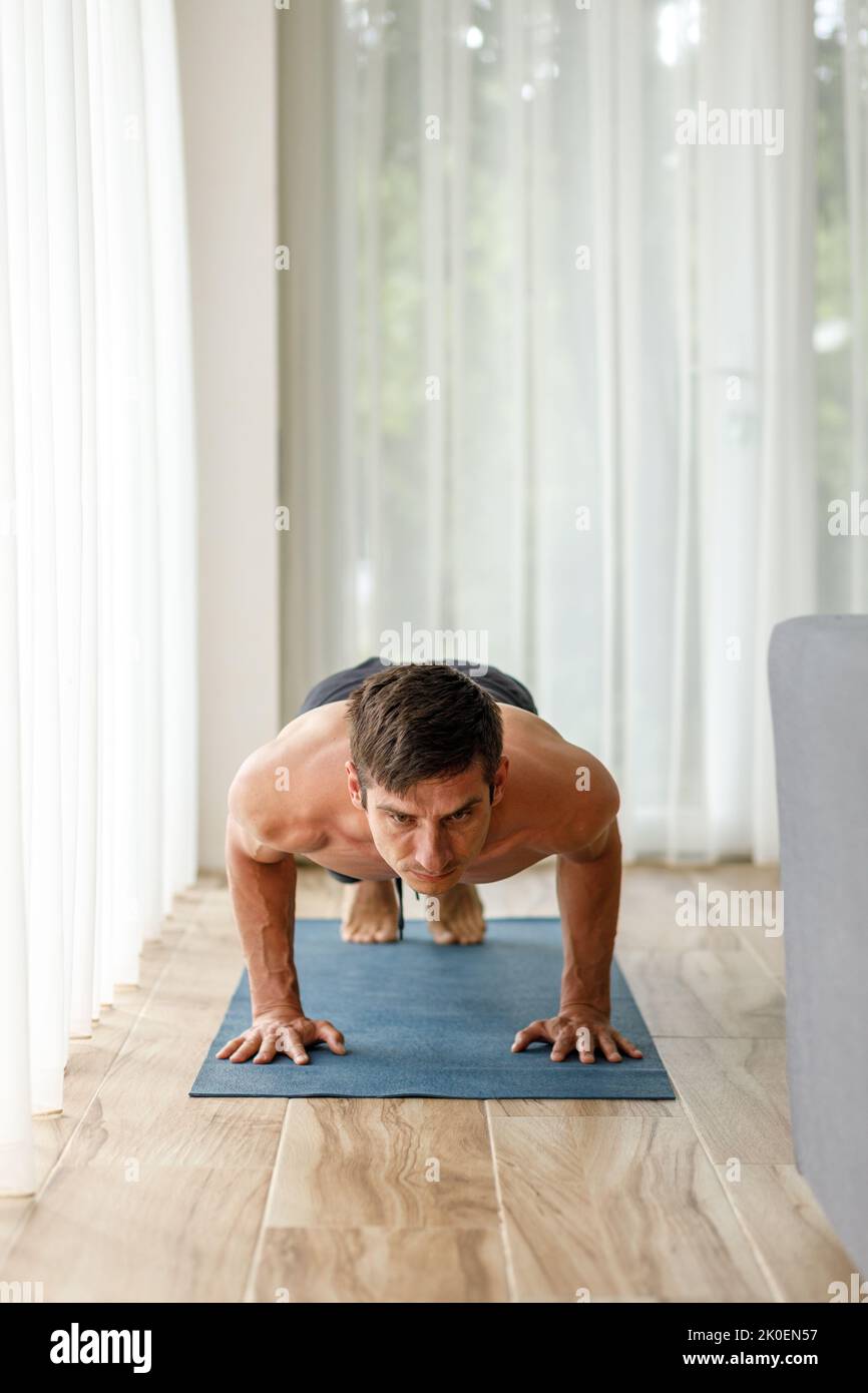 Mann mittleren Alters, der während seiner morgendlichen körperlichen Routine Chaturanga-Yoga-Pose ausführt Stockfoto