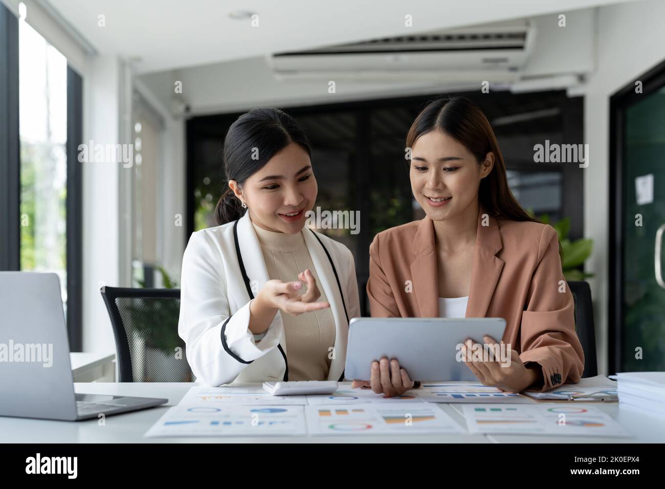 Asiatischer Berater zeigt dem Partner im Beratungsbüro den Investitionsplan. Konzept für die Zusammenarbeit im Unternehmen. Stockfoto