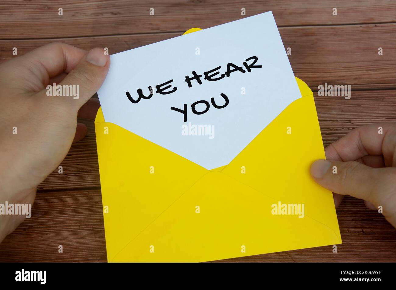 Wir hören Sie Text auf weißem Notizblock in gelbem Umschlag. Zuhörkonzept. Stockfoto