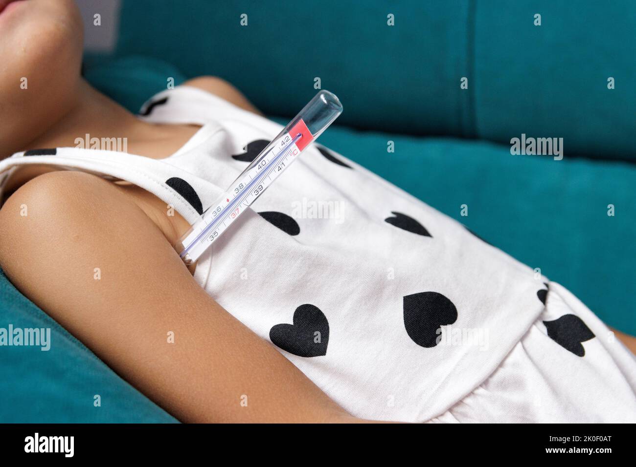 Mädchen mit Fieber auf dem Sofa mit Thermometer in ihrer Achsel Stockfoto