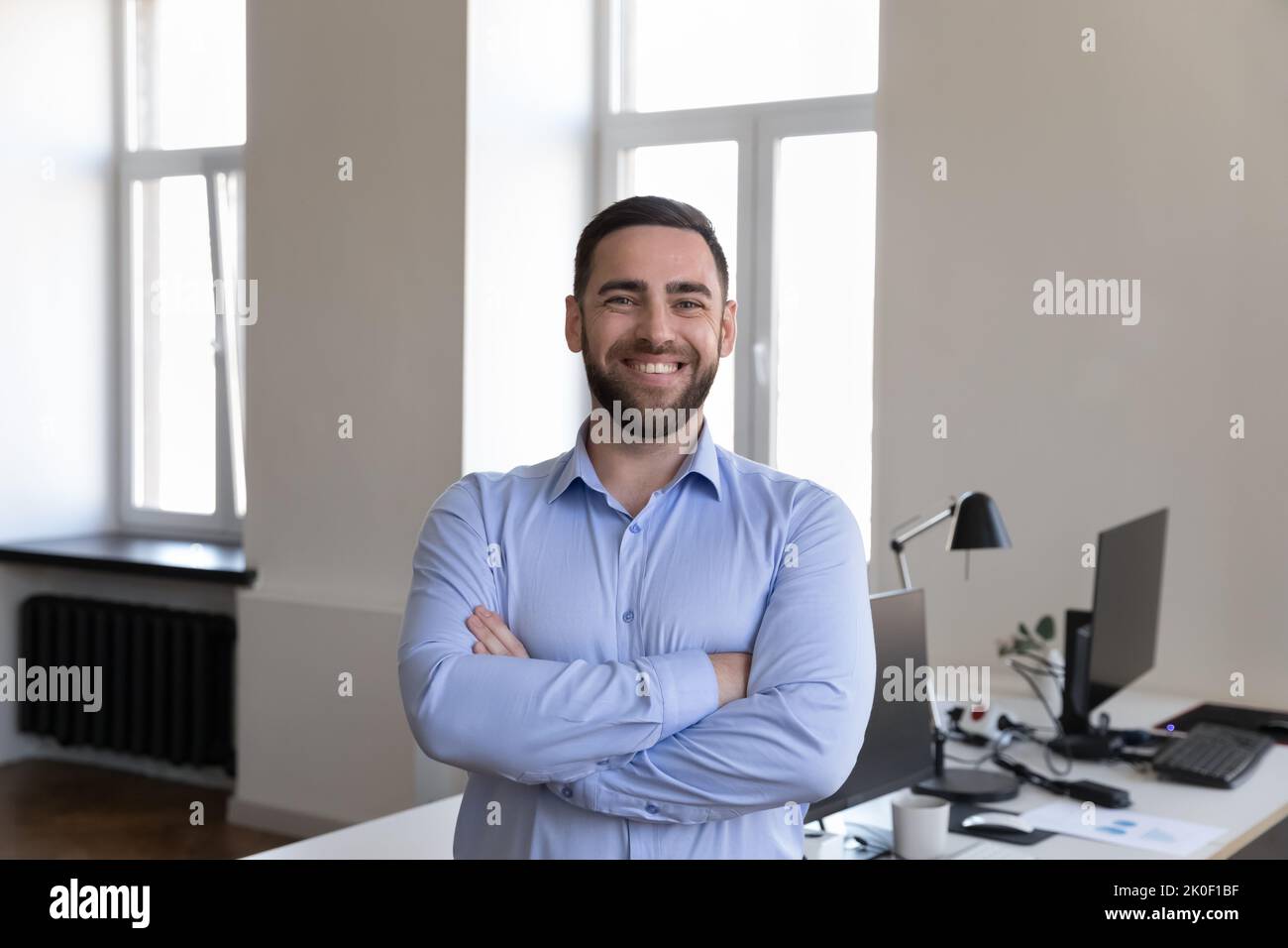 Glücklicher, gutaussehender Geschäftsmann, der die Kamera anschaut und lächelnd posiert Stockfoto