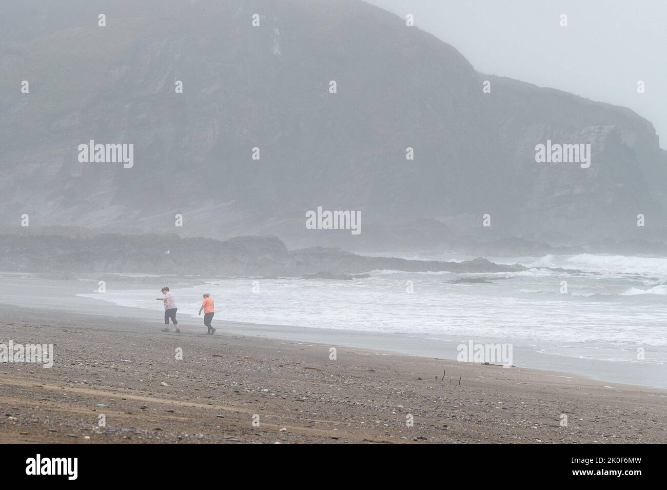 Owenahincha, West Cork, Irland. 11. September 2022. Zwei Frauen laufen heute unter einer orangen Wetterwarnung am Strand von Owenahincha entlang. Met Éireann hat seitdem die Wetterwarnung abgesagt, da der Regen heute Nachmittag nachgelassen hat. Quelle: AG News/Alamy Live News Stockfoto