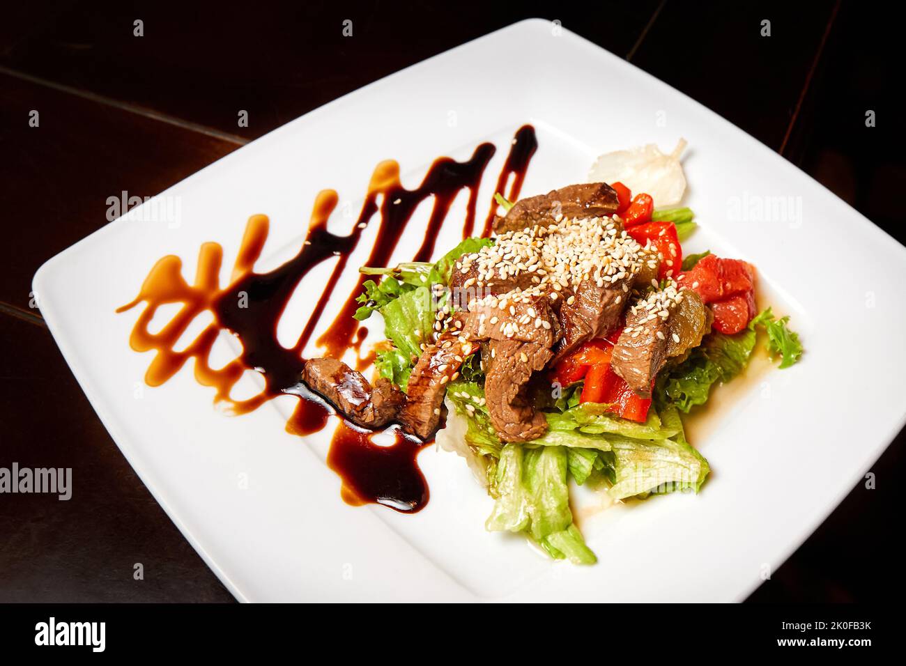 Stücke geschmortes Rindfleisch mit rotem Paprika und Salat in einer würzigen Sauce Stockfoto