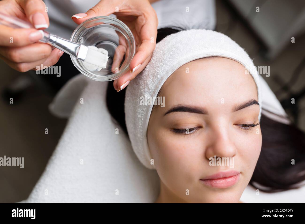 Nahaufnahme einer Frau, die eine Gesichtsbehandlung mit Tonmaske erhält. Kosmetologie und Spa Stockfoto