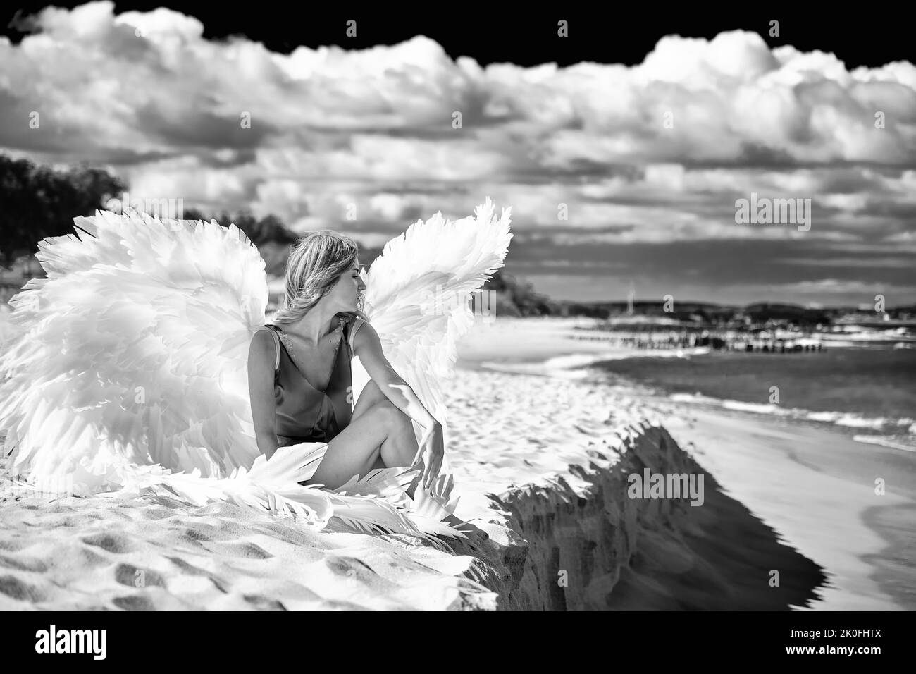 Eine junge schöne Frau Engel mit weißen Flügeln an der Küste monochrom Stockfoto