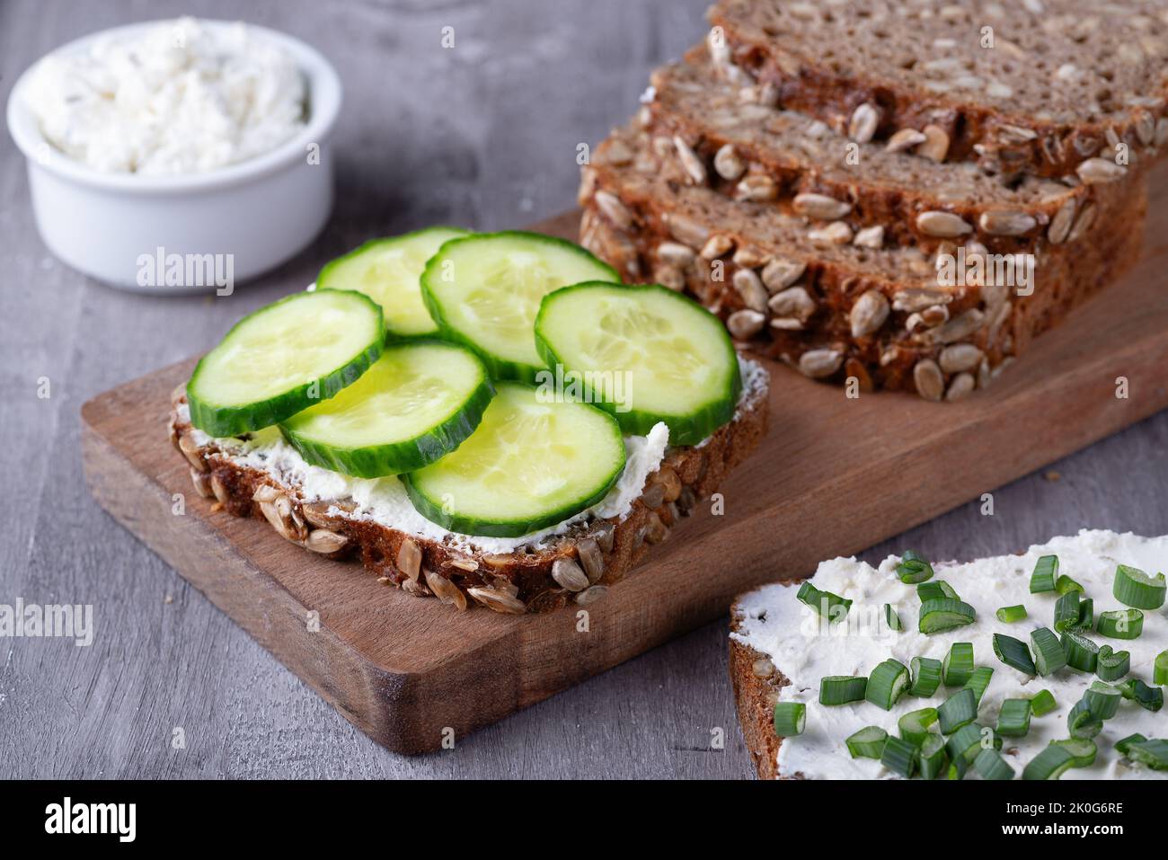 Roggenbrotscheiben mit Quark und Gurken auf grauem Hintergrund Stockfoto