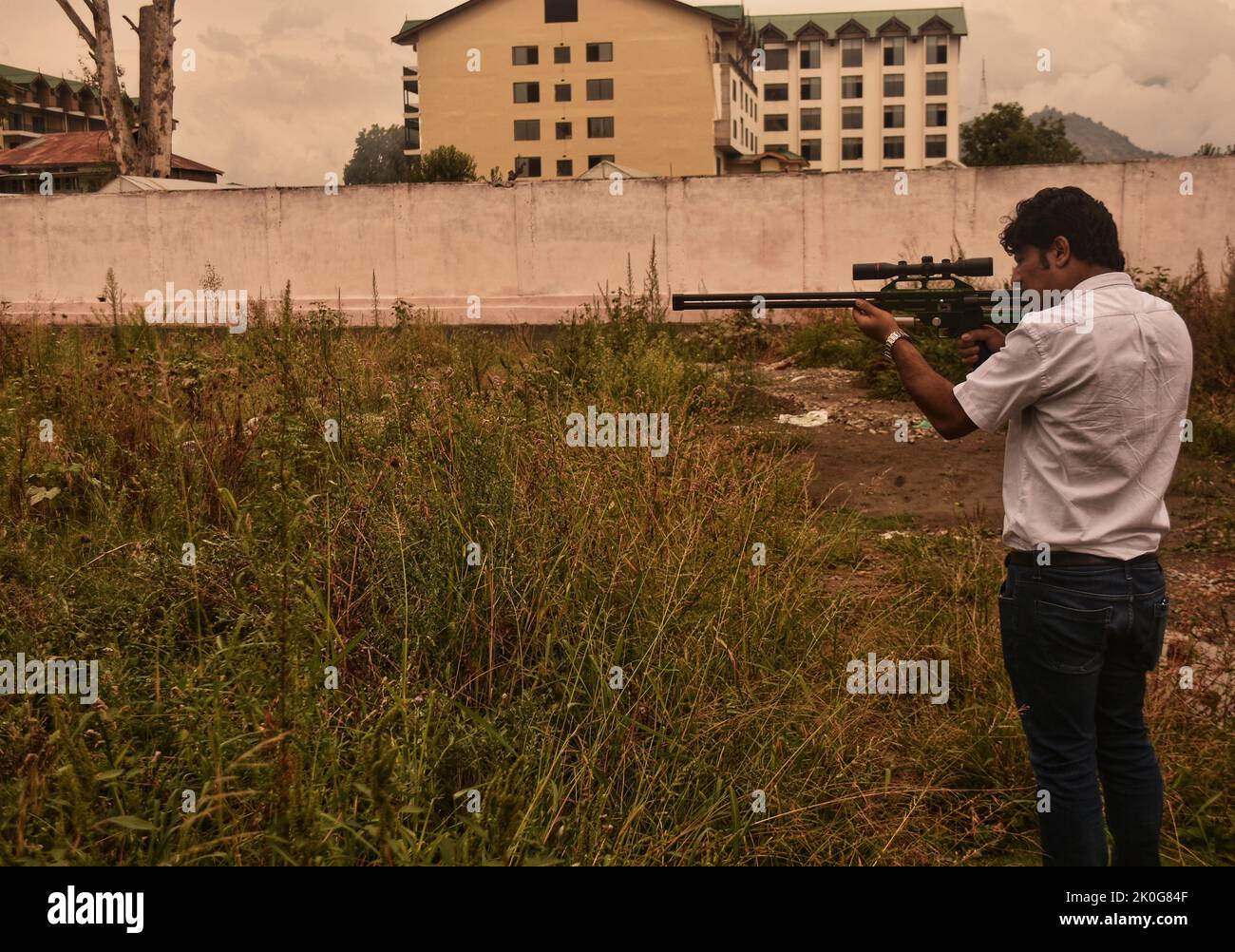 11. September 2022, Srinagar, Jammu and Kashmir, Indien: Wildtierbeamter versteckt sich in der Nähe des Zauns, während er auf der Suche nach einem wilden Bären ein Beruhigungsmittel-Dartgewehr auf einen verdächtigen Ort abzielte, nachdem ein Zivilist bei seinem Angriff in Srinagar, dem von Indien kontrollierten Kaschmir, am Sonntag, den 11. September 2022 verletzt wurde. (Bild: © Mubashir Hassan/Pacific Press via ZUMA Press Wire) Stockfoto