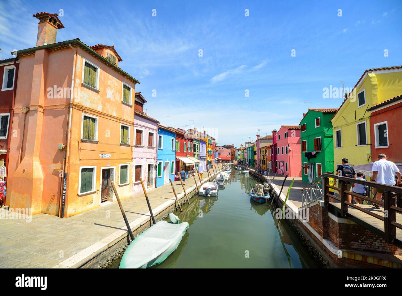 BURANO ISLAND, VENEDIG, ITALIEN - 4. JULI 2022: Touristen unter den souveränen Geschäften auf der Hauptstraße der insel burano, bunte Häuser am Kanal. Fa Stockfoto