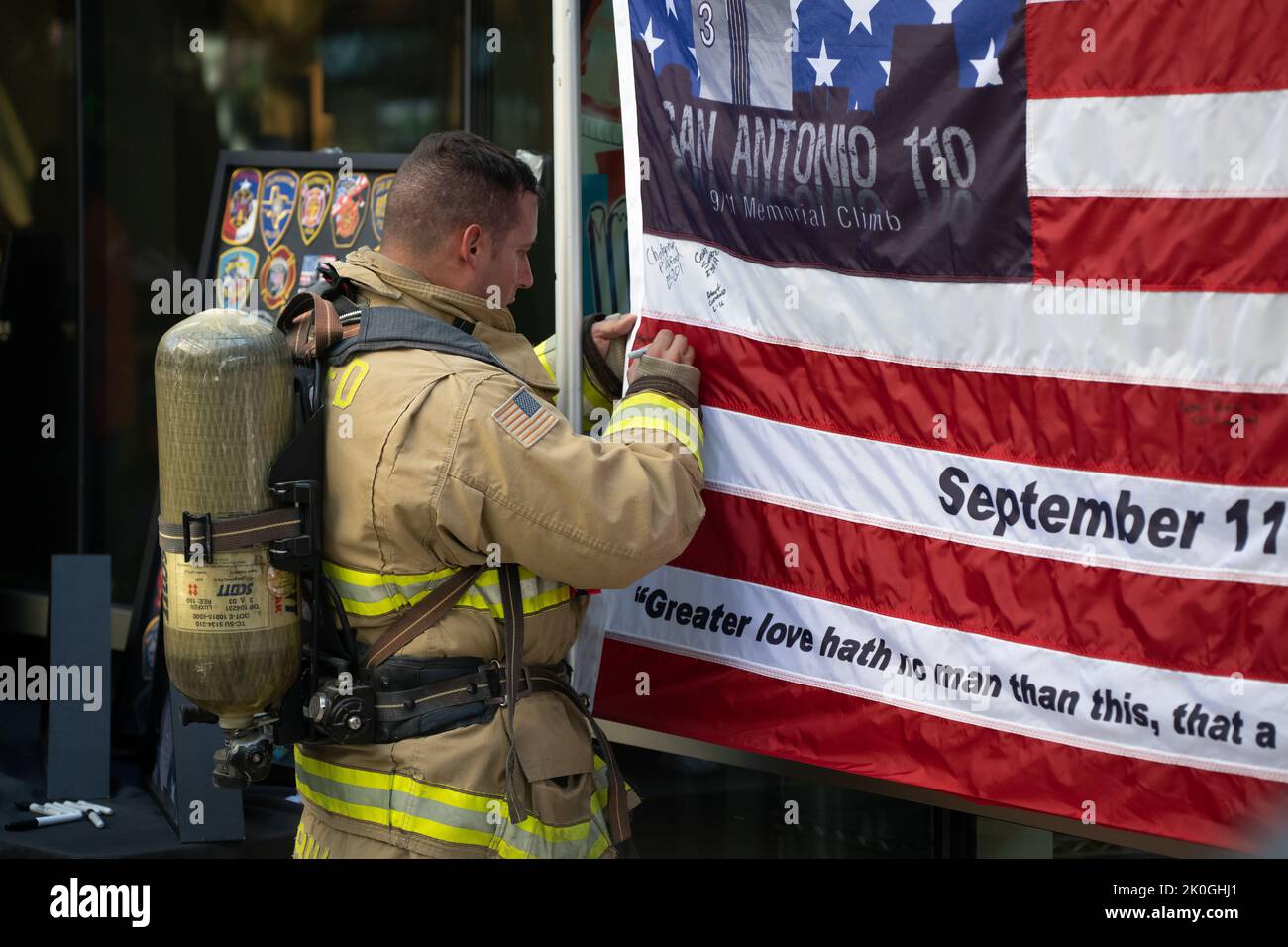 Ein Feuerwehrmann signiert eine Gedenkflagge, nachdem er an der San Antonio 110 9/11 Gedenkstätte teilgenommen hat, die den Tower of the Americas hochklettert. Stockfoto