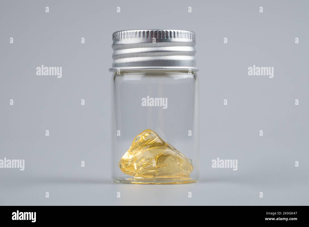 Piace Cannabisextrakt Wachs mit transparenter Flasche Nahaufnahme auf grauem Hintergrund. Stockfoto