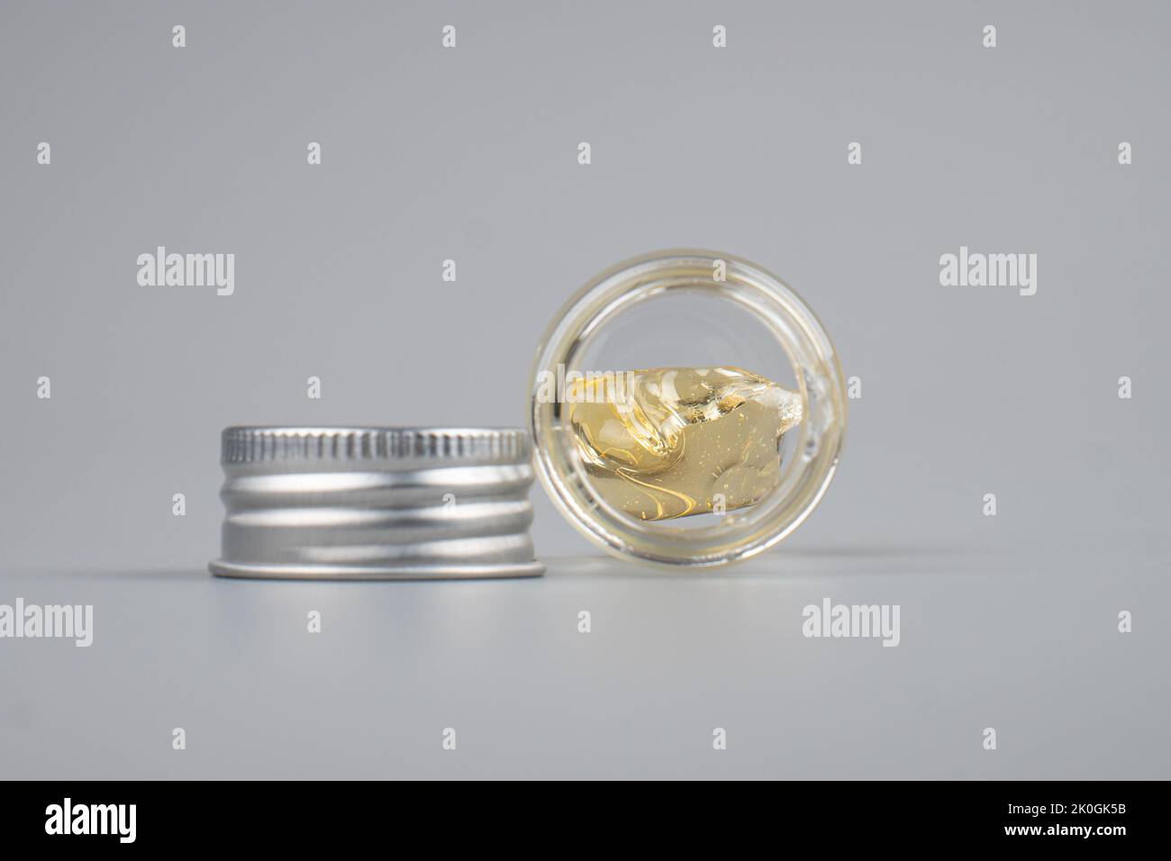 Piace Cannabisextrakt Wachs mit transparenter Flasche Nahaufnahme auf grauem Hintergrund. Stockfoto