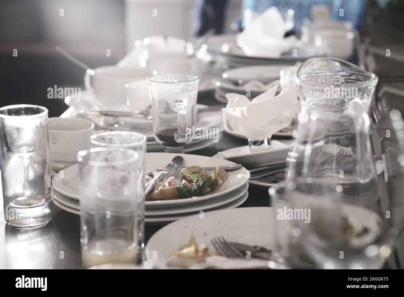 Schmutzige Teller und Gläser nach dem Essen in der Küche im Restaurant. Haufen oder Haufen von unsauberem Glas und Teller mit Frühstück oder Lunch-Tisch Stockfoto