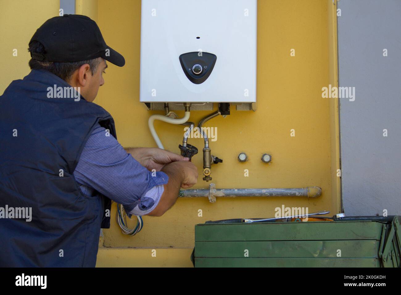 Klempner auf einer Leiter während der Reparatur und Wartung eines Gaskessels in Erwartung des Winters. Austausch einer zentralen Heizungsleitung Stockfoto