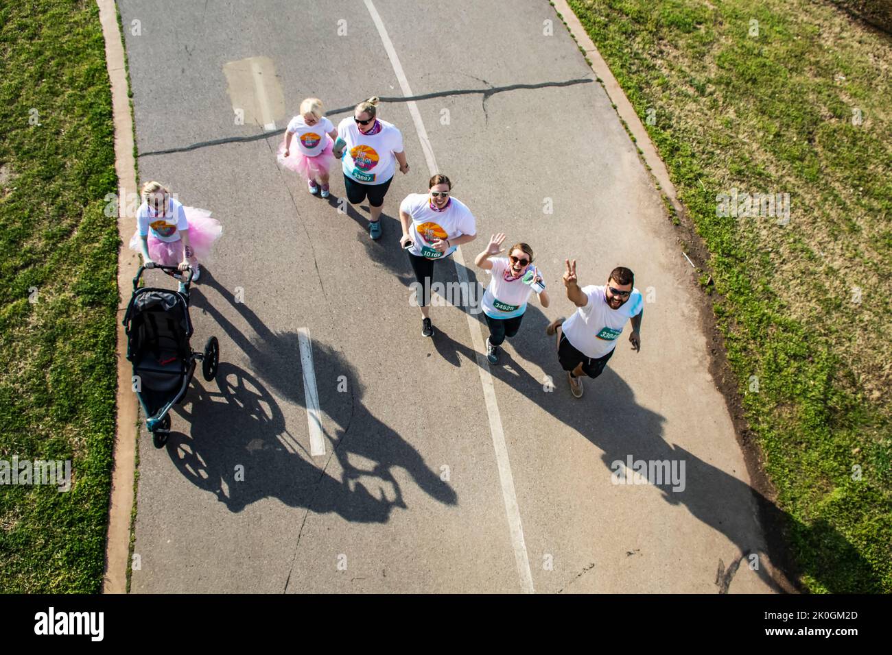 4-6-2019 Tulsa - Teilnehmer am Color Run von oben betrachtet mit dramatischen Schatten, die aufblicken und winken und Friedenszeichen geben - Gruppe umfasst eine kleine Gruppe Stockfoto