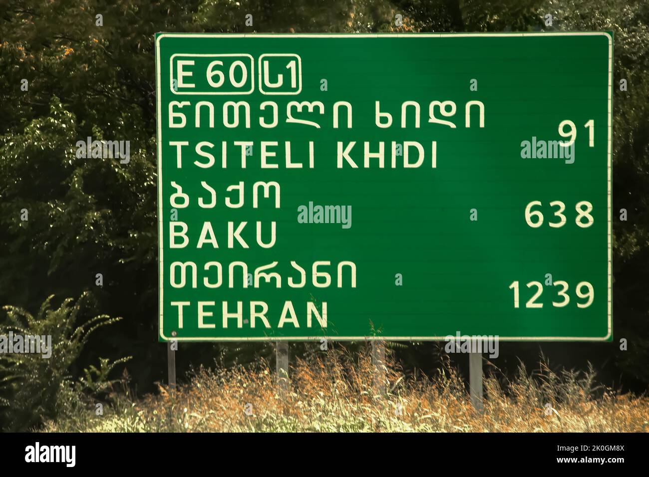 Straßenschild mit Entfernungen nach Baku und Teheran und Tsiteli Khidi in mehreren Schriften - in der Nähe von Tiflis Georgien Stockfoto