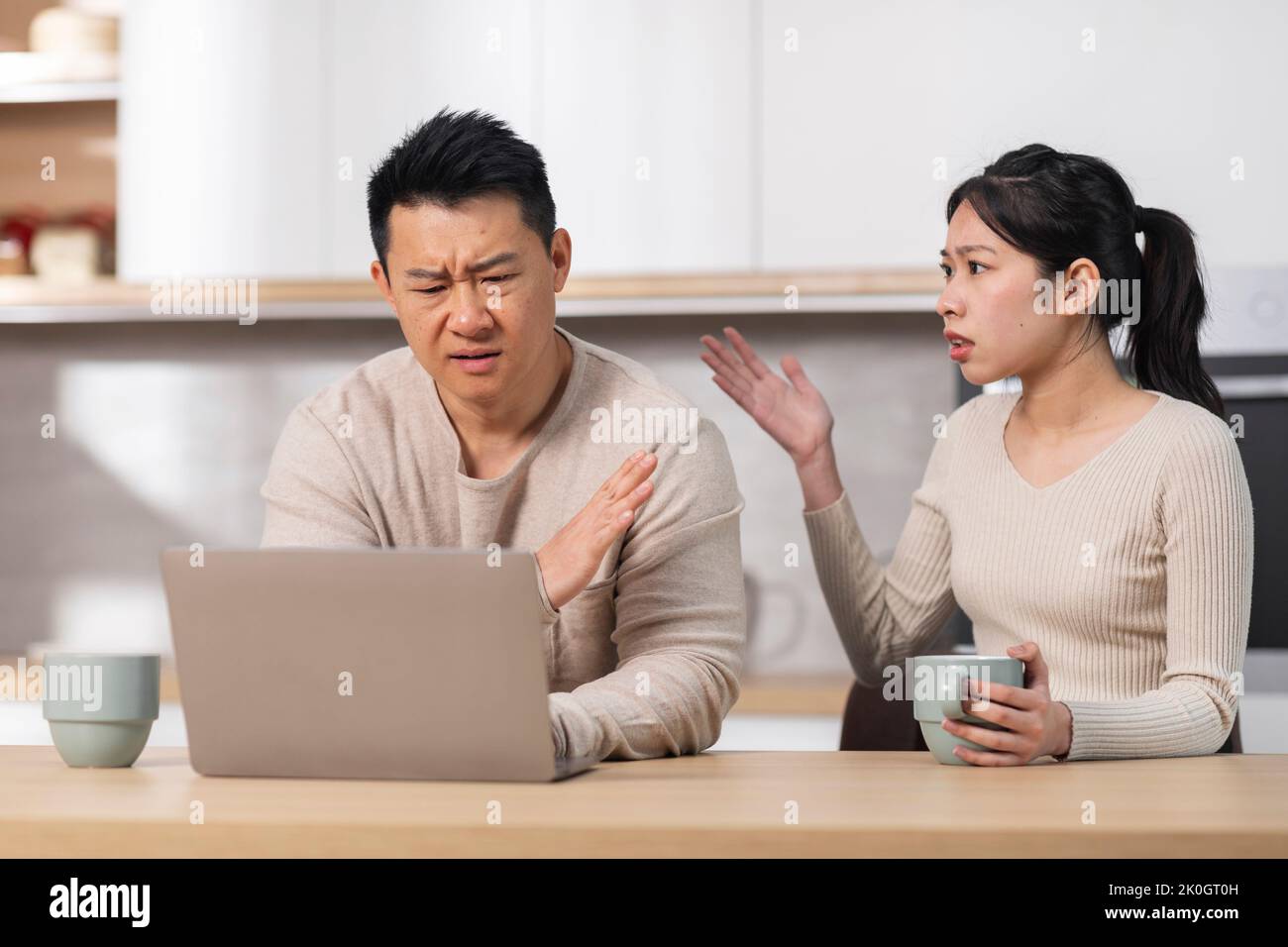 Wütende asiatische Frau, die ihren Mann mit einem Laptop anschrie Stockfoto
