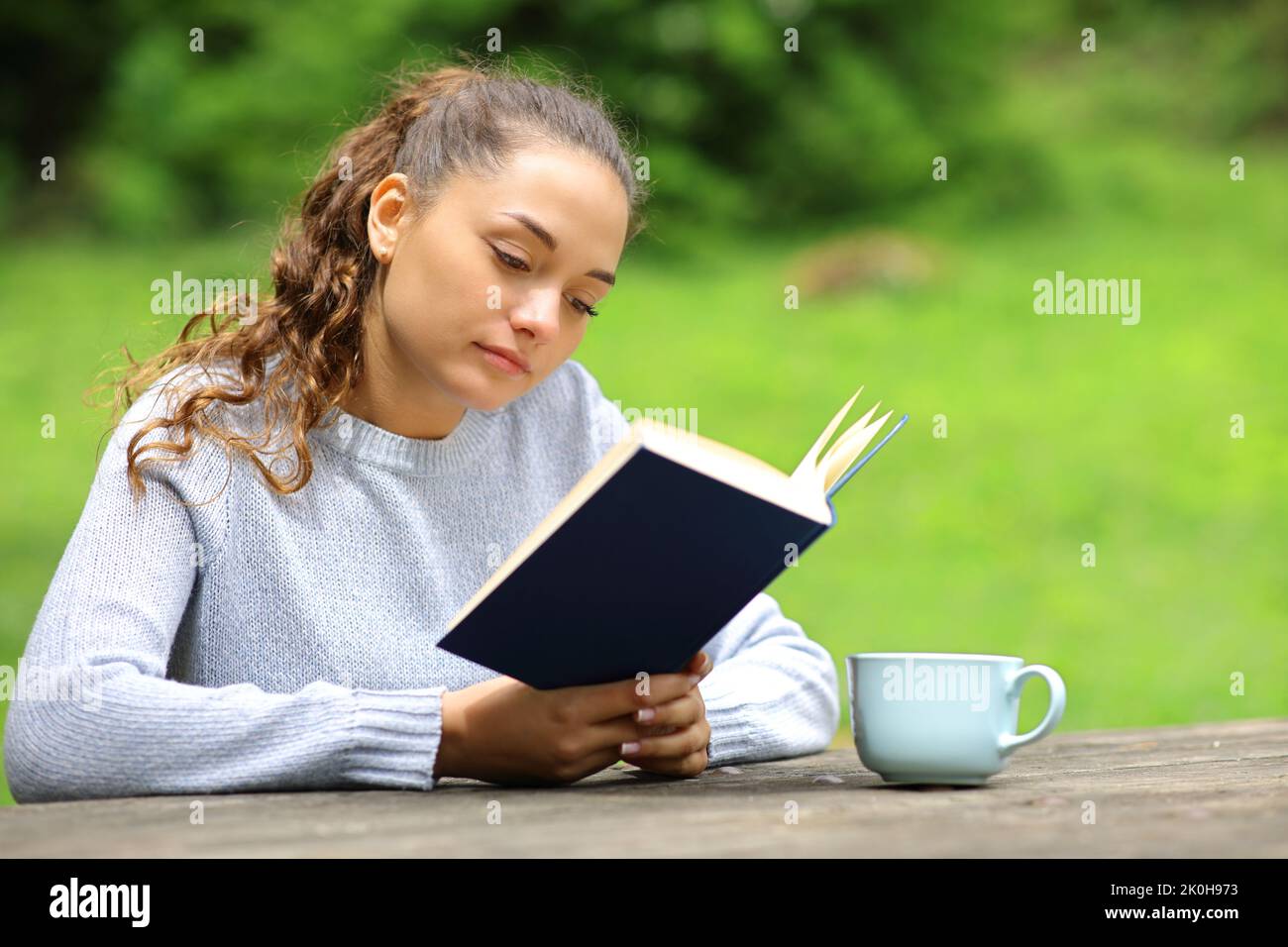 Entspannte Frau in einem Park oder Camping, die ein Buch liest Stockfoto