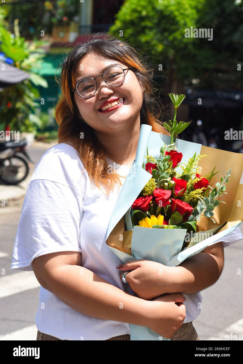 Glückliche vietnamesische wunderschöne Frau mit Blumenstrauß Stockfoto