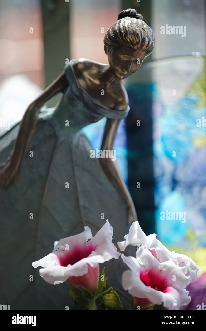 Eine vertikale Aufnahme einer Feenfigur neben Blumen Stockfoto