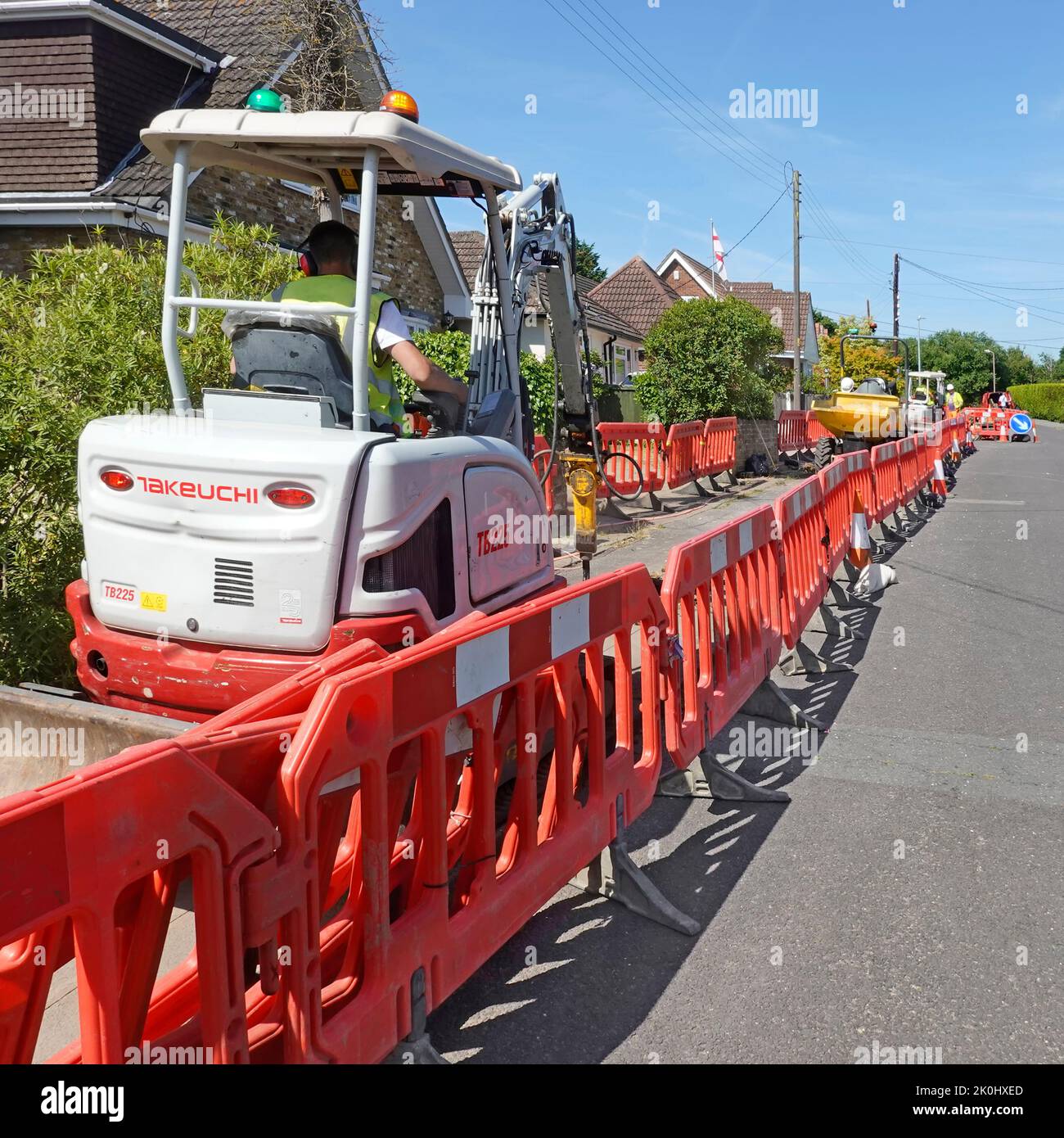 Rote Verriegelungsstraße arbeitet Kunststoff-Sicherheitsbarrieren Beschränkung Hausbesitzer Crossover-Zugang Mini-Bagger graben Breitband-Graben in Bürgersteig Großbritannien Stockfoto