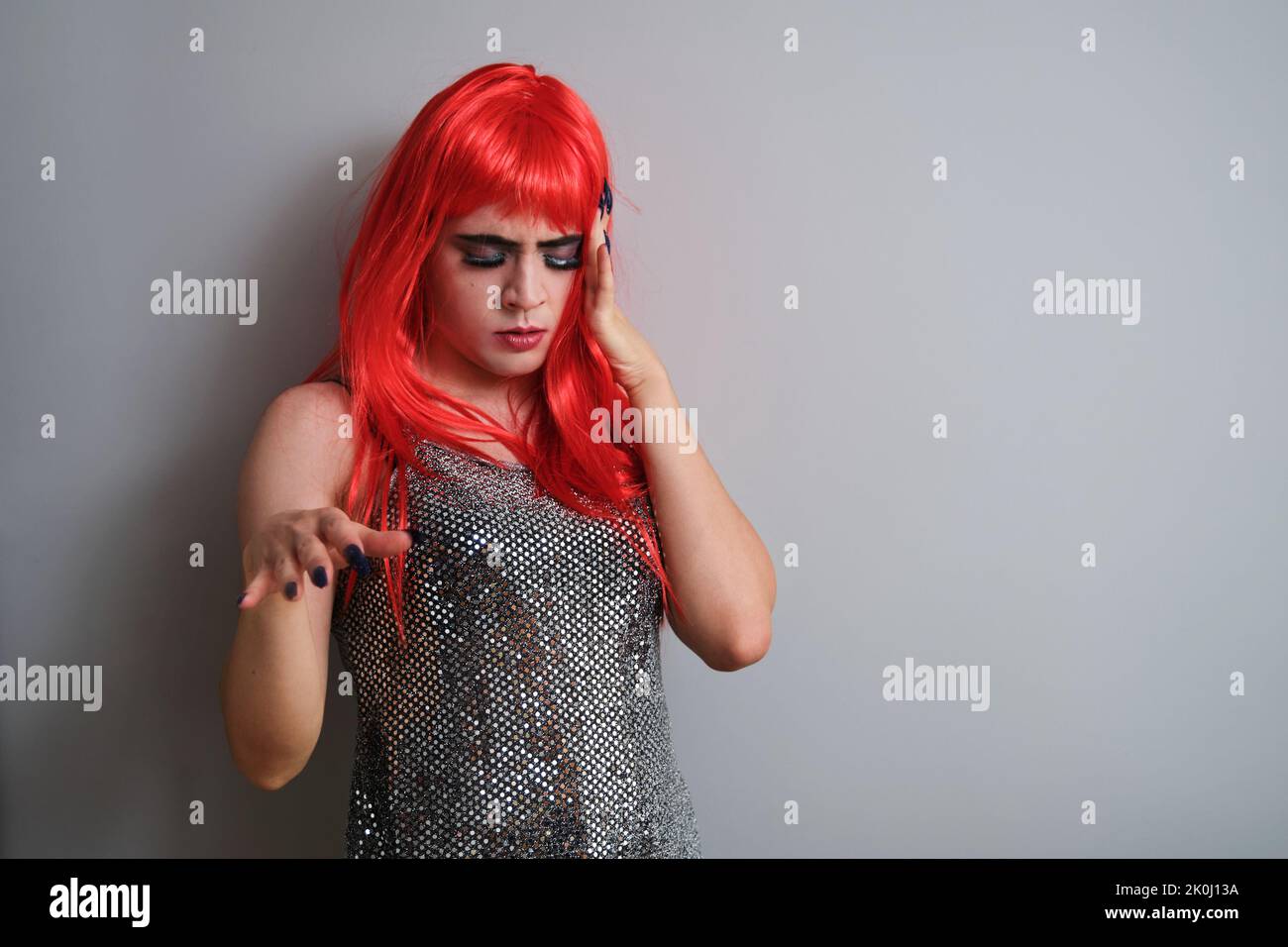 Porträt eines Transgender-Mannes, der tanzt und eine rote Perücke trägt. Stockfoto