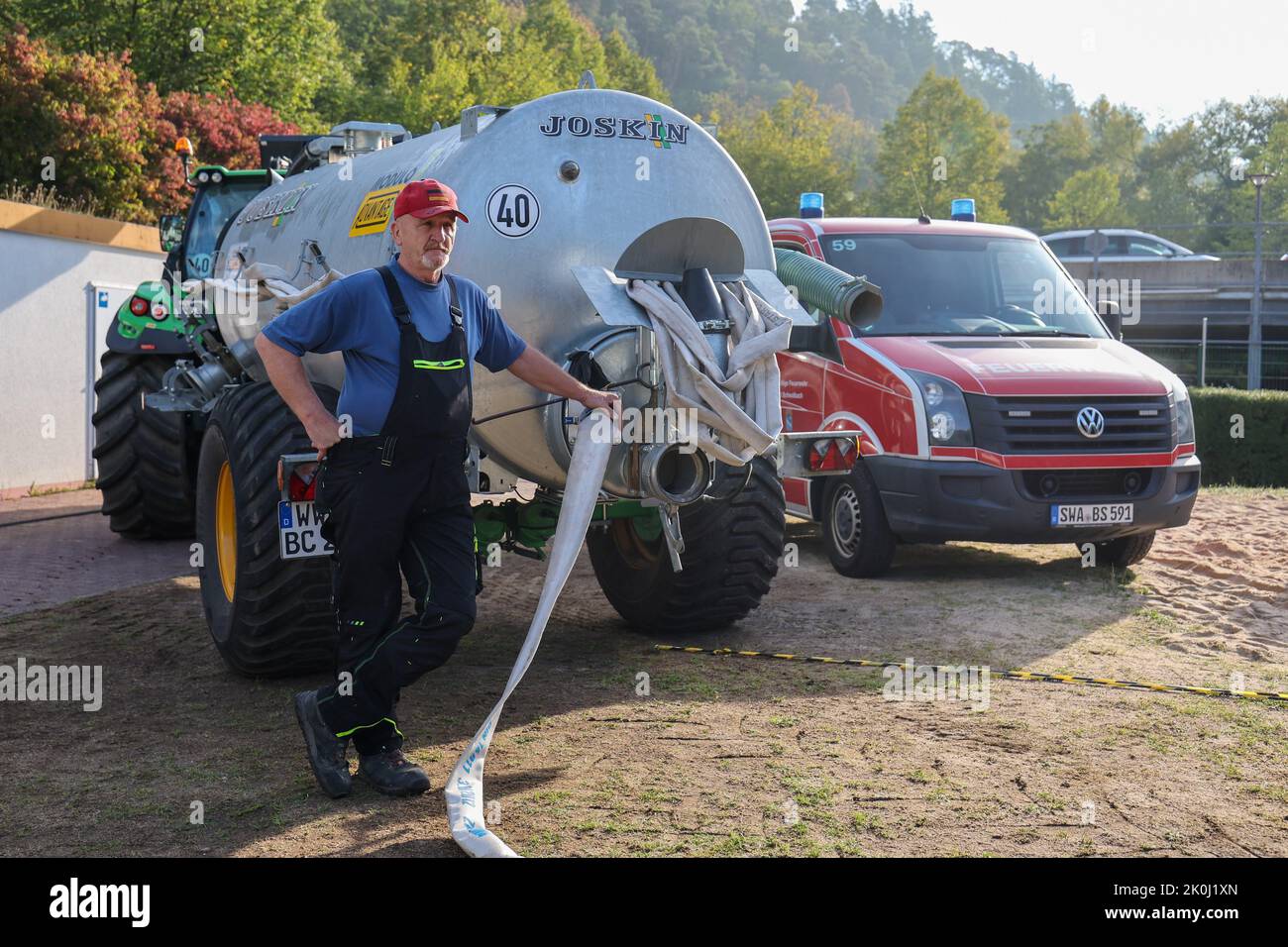 Bad Schwalbach, Deutschland. 12. September 2022. Benno Burggraf steht an  seinem Traktor mit Wasserbehälter und holt mit einer Pumpe Wasser aus dem  Becken von der Feuerwehr, um dann die Bäume im Kurpark