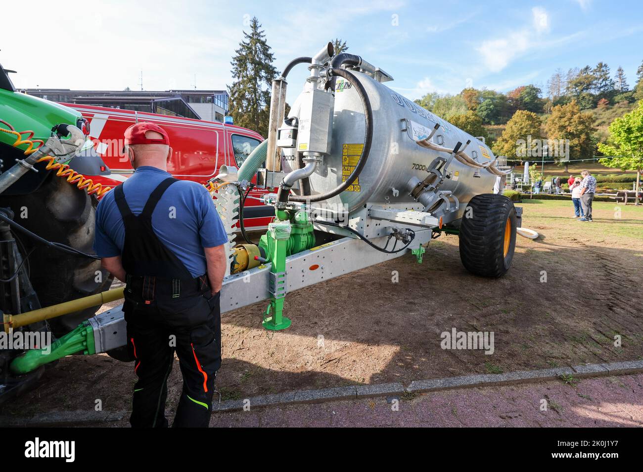 Bad Schwalbach, Deutschland. 12. September 2022. Benno Burggraf steht an  seinem Traktor mit Wasserbehälter und holt mit einer Pumpe Wasser aus dem  Becken von der Feuerwehr, um dann die Bäume im Kurpark