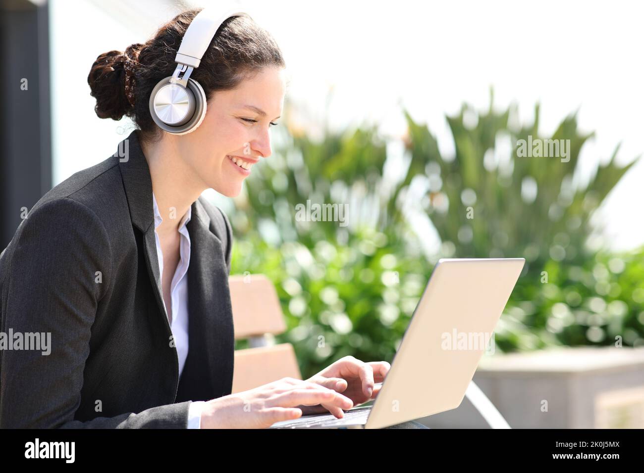 Executive-Zimmer mit kabellosen Kopfhörern mit Laptop in einem Park Stockfoto