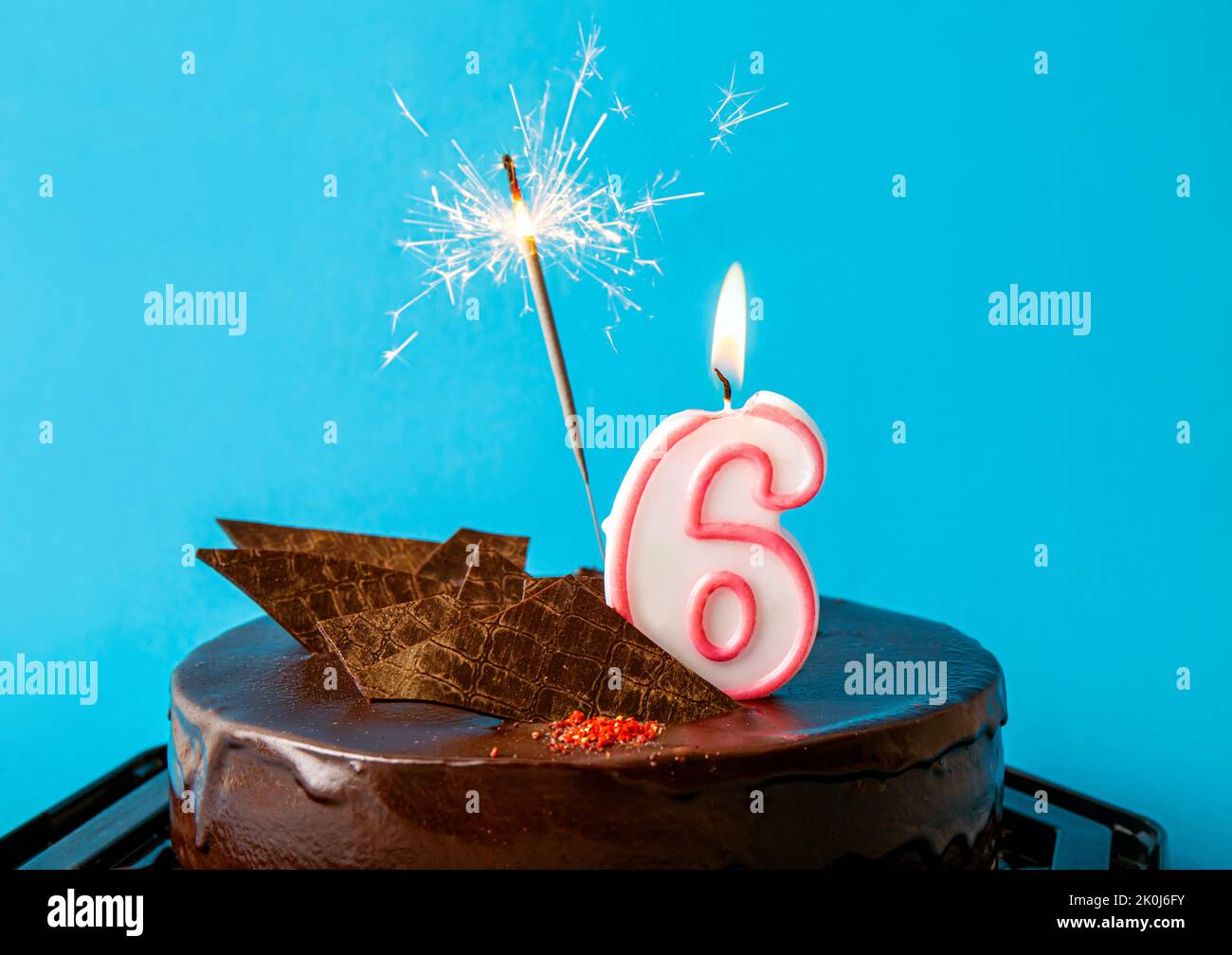 Nummer 6 Geburtstagskerze brennt und funkelt mit Funken auf Kuchen. Konzept zum sechsten Geburtstag der Jubiläumsfeier. Viel Kopierplatz auf Blau. Stockfoto