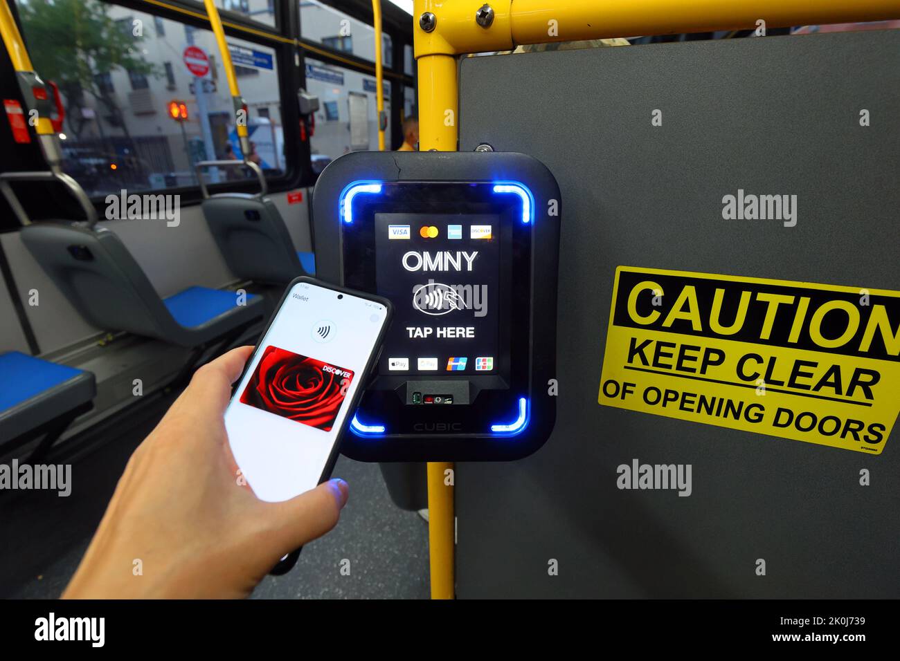 Ein NFC-fähiges Smartphone mit Google Wallet tippt auf einem NYC Transit-Bus auf einen OMNY kontaktlosen Bezahlleser. Stockfoto