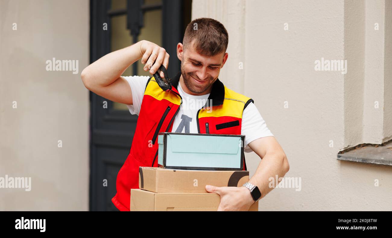 Der glückliche Kurier scannt ein Barcode-Paket mit einem tragbaren Barcode-Scanner Stockfoto