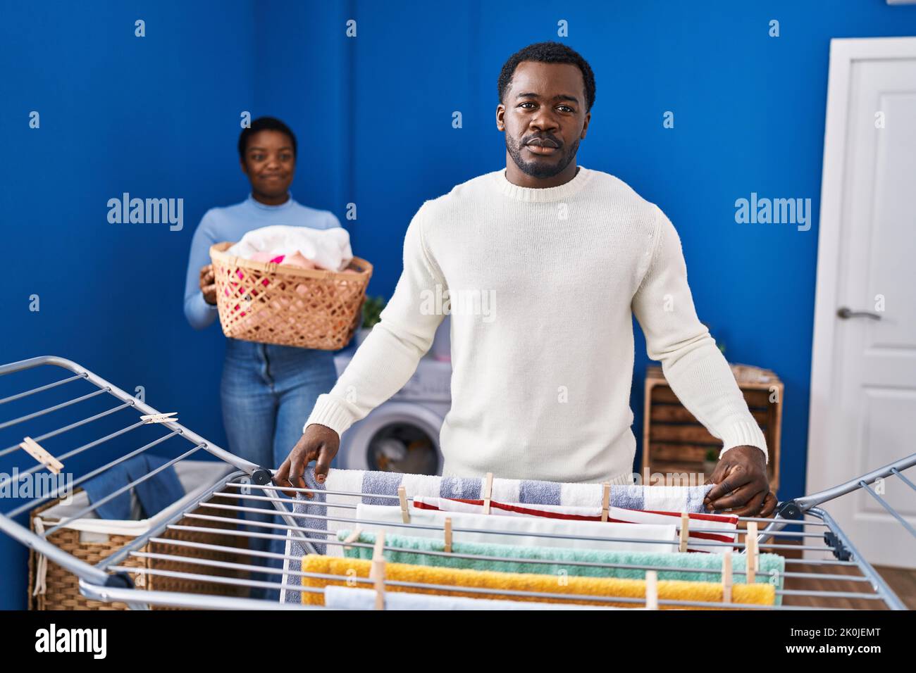 Junge afroamerikanische Paar hängende Kleidung an Wäscheleine Denken Haltung und nüchternen Ausdruck selbstbewusst aussehen Stockfoto