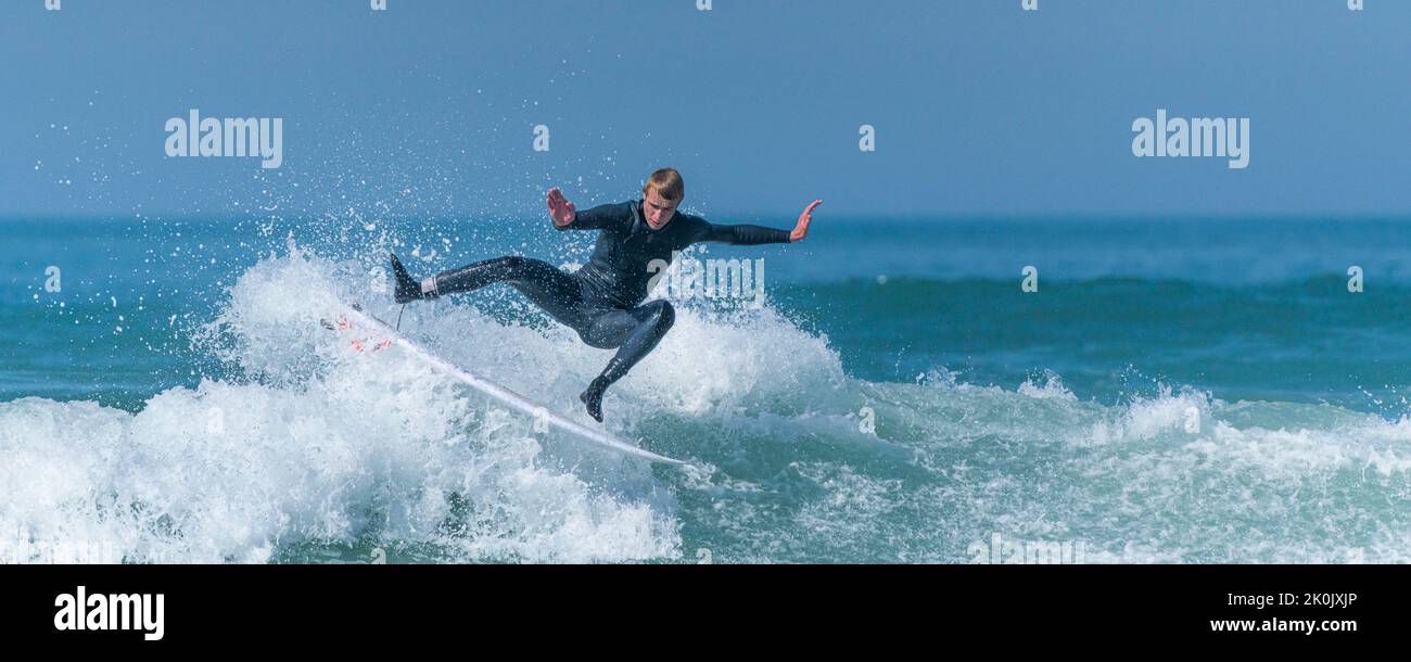 Ein Panoramabild von spektakulärer Surfing-Action, während ein Surfer eine Welle im Fistral in Newquay in Cornwall in Großbritannien reitet. Stockfoto